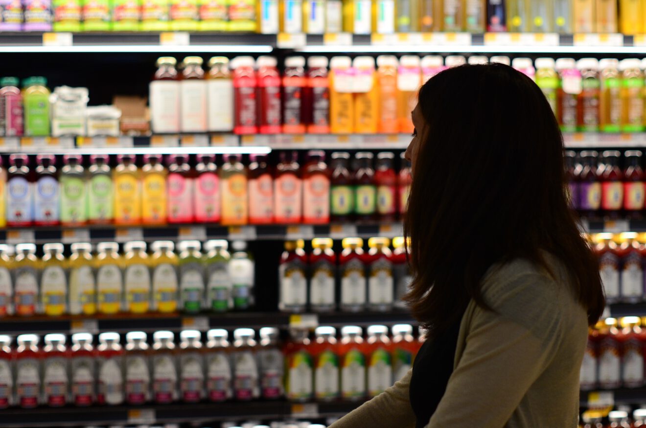 Q&A: The impact of price increases on retailers and manufacturers [Image: Woman looking over a shelf of bottled beverages]