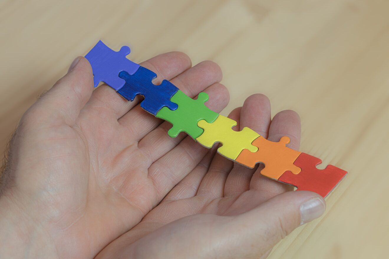 Child holding rainbow colored puzzle pieces
