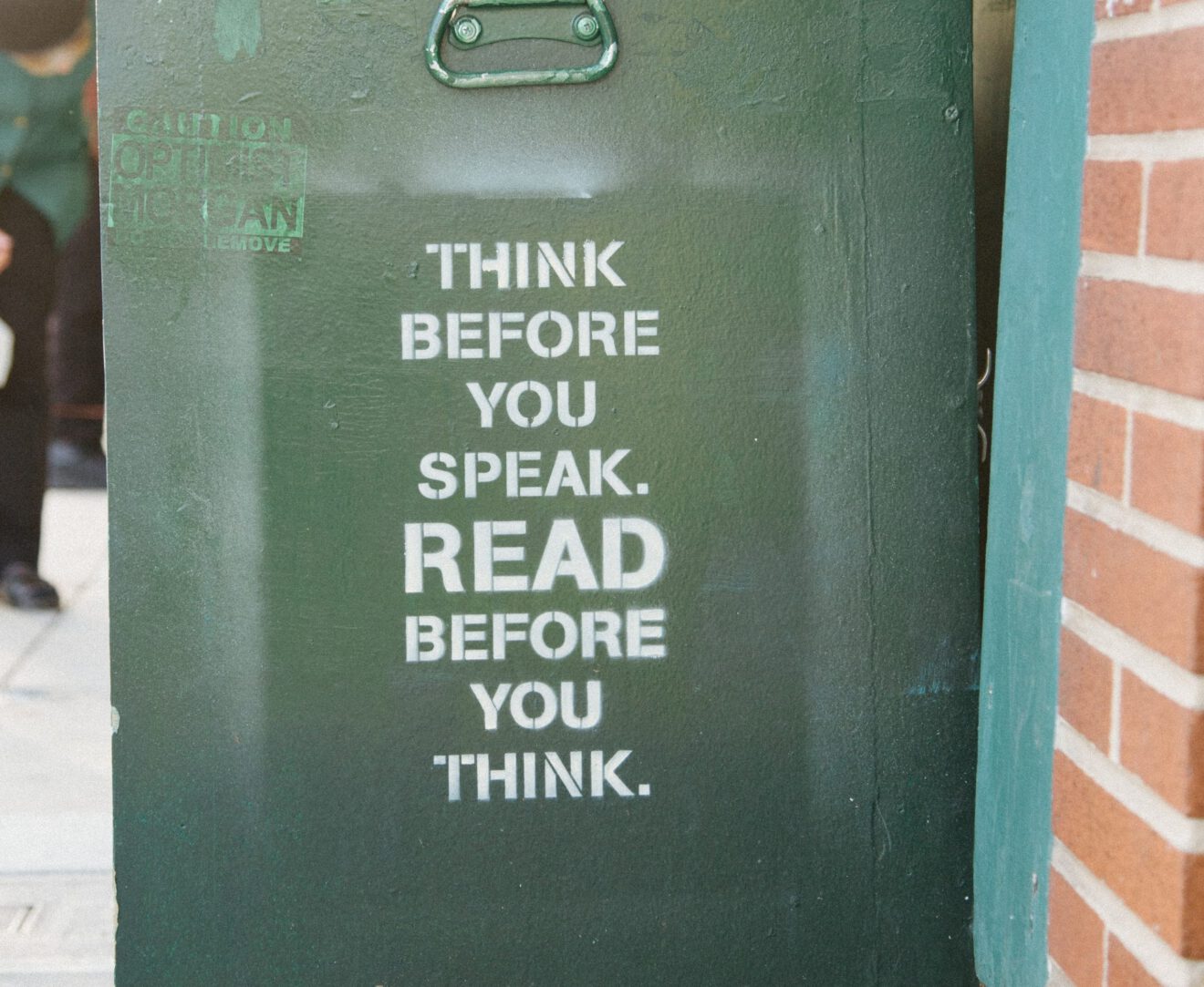 Wheeled janitorial bin with stencil reading "Think before you speak; read before you think" for teaching amid political divisiveness article
