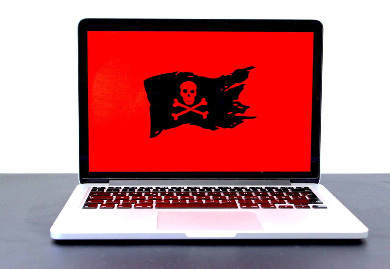 Laptop with black skull and crossbones on red background for education cybersecurity article