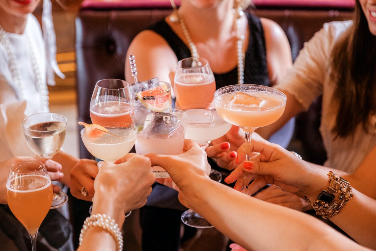 A group of people cheers with cocktails and mocktails