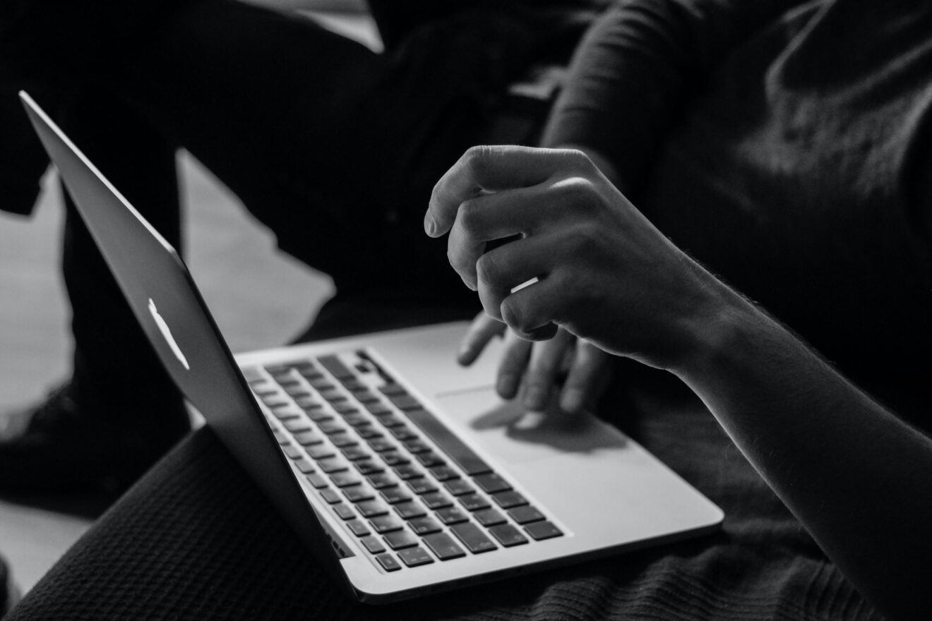 Black-and-white photo of hands on a laptop computer for implementing online tutoring article