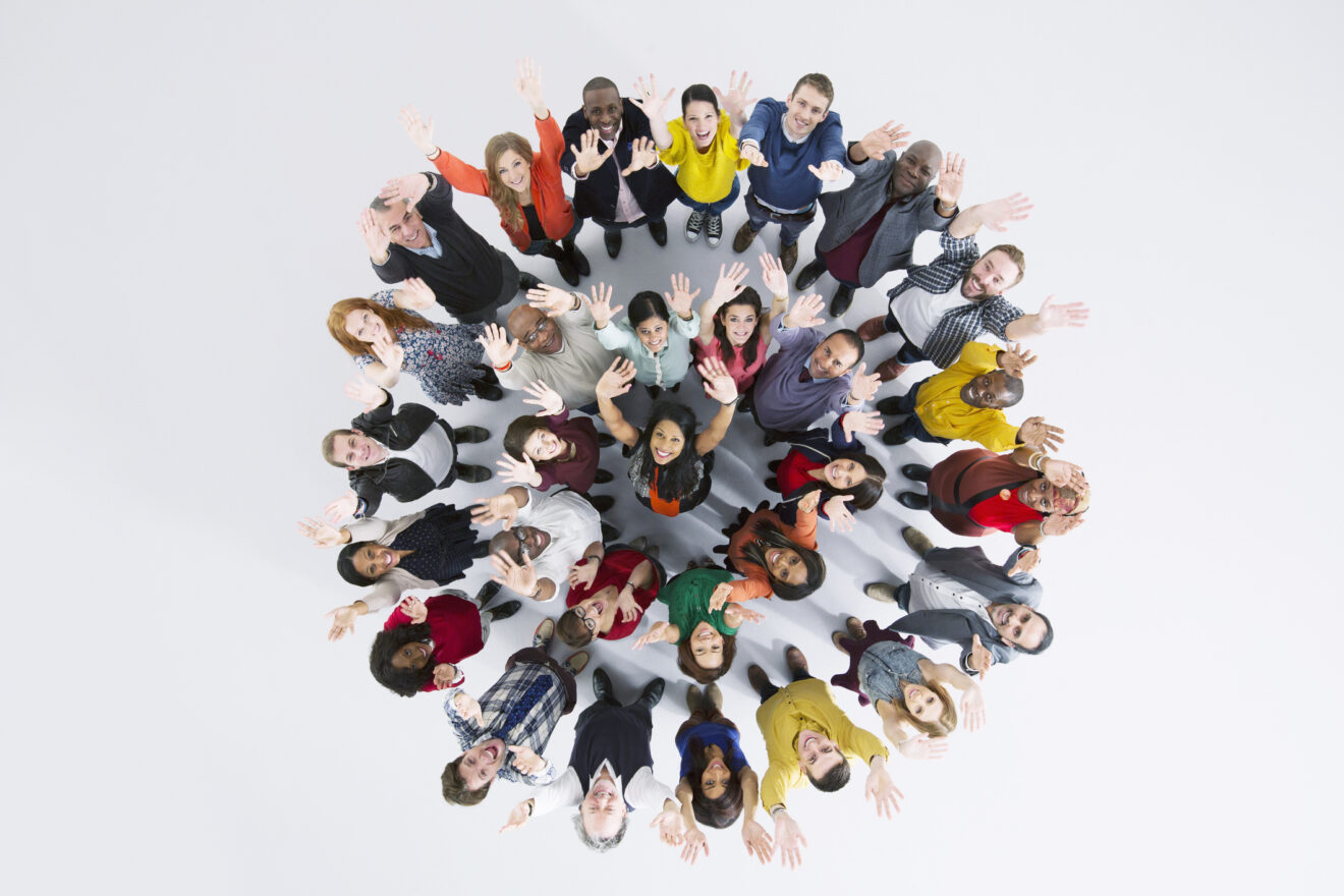 circle within circle of enthusiastic people with arms in the air for article on nuances of belonging