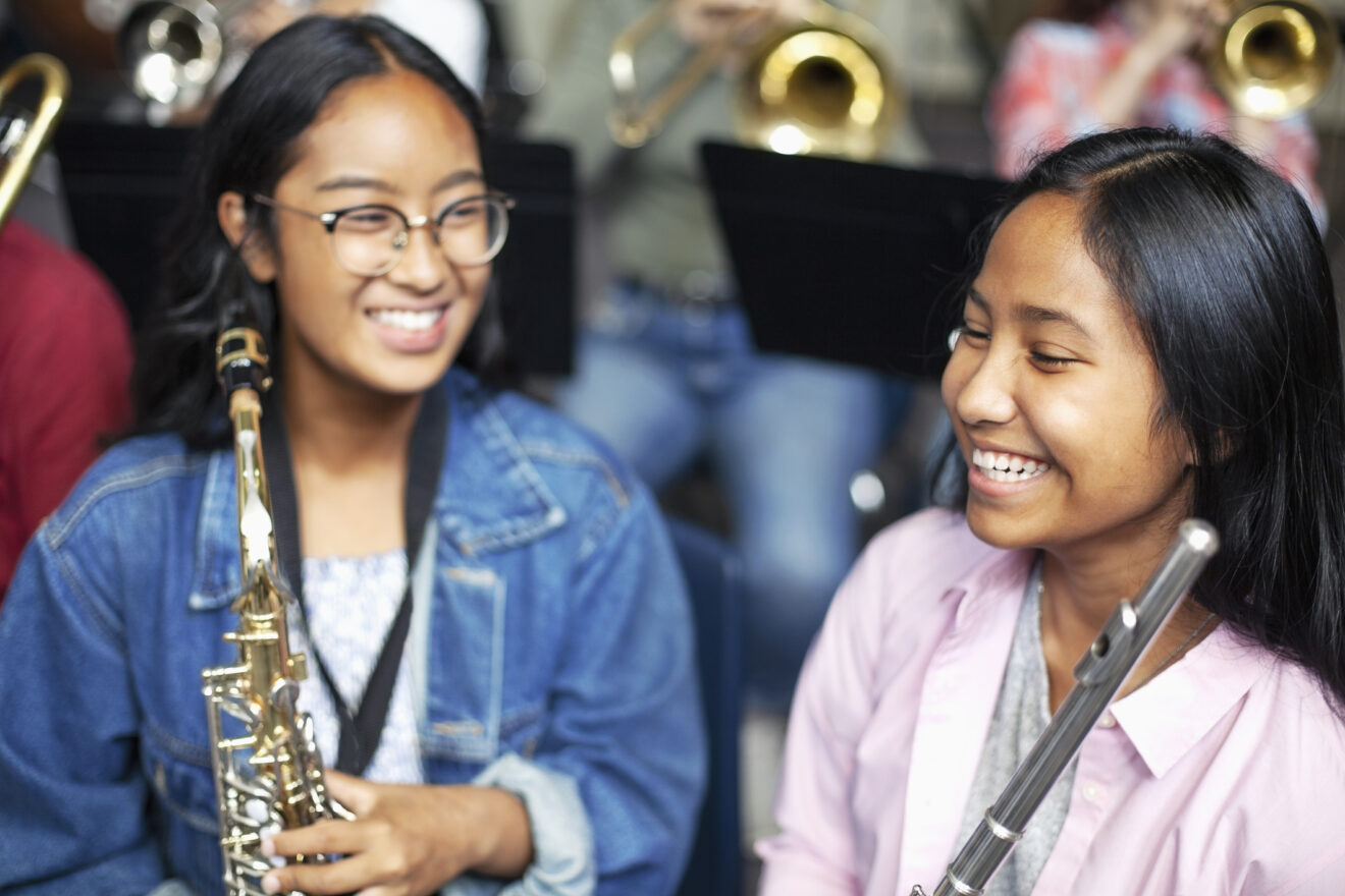 Two teenagers playing musical instruments in band class.