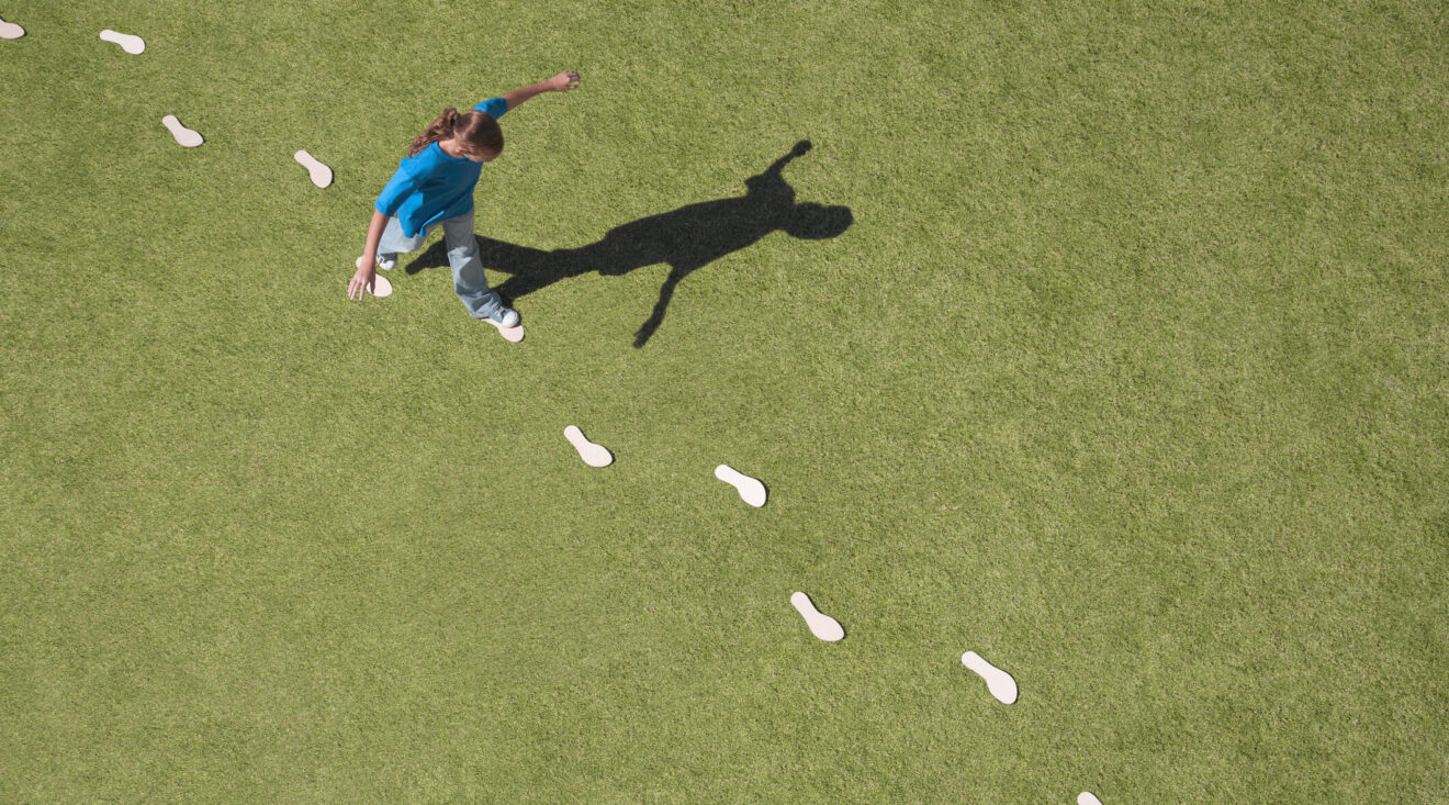 Student following in white footprints across green grass for article on Simulation Day preparing for new school year