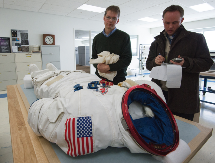 Two men looking at a spacesuit worn for 60 days in space on the SkyLab in 1973.