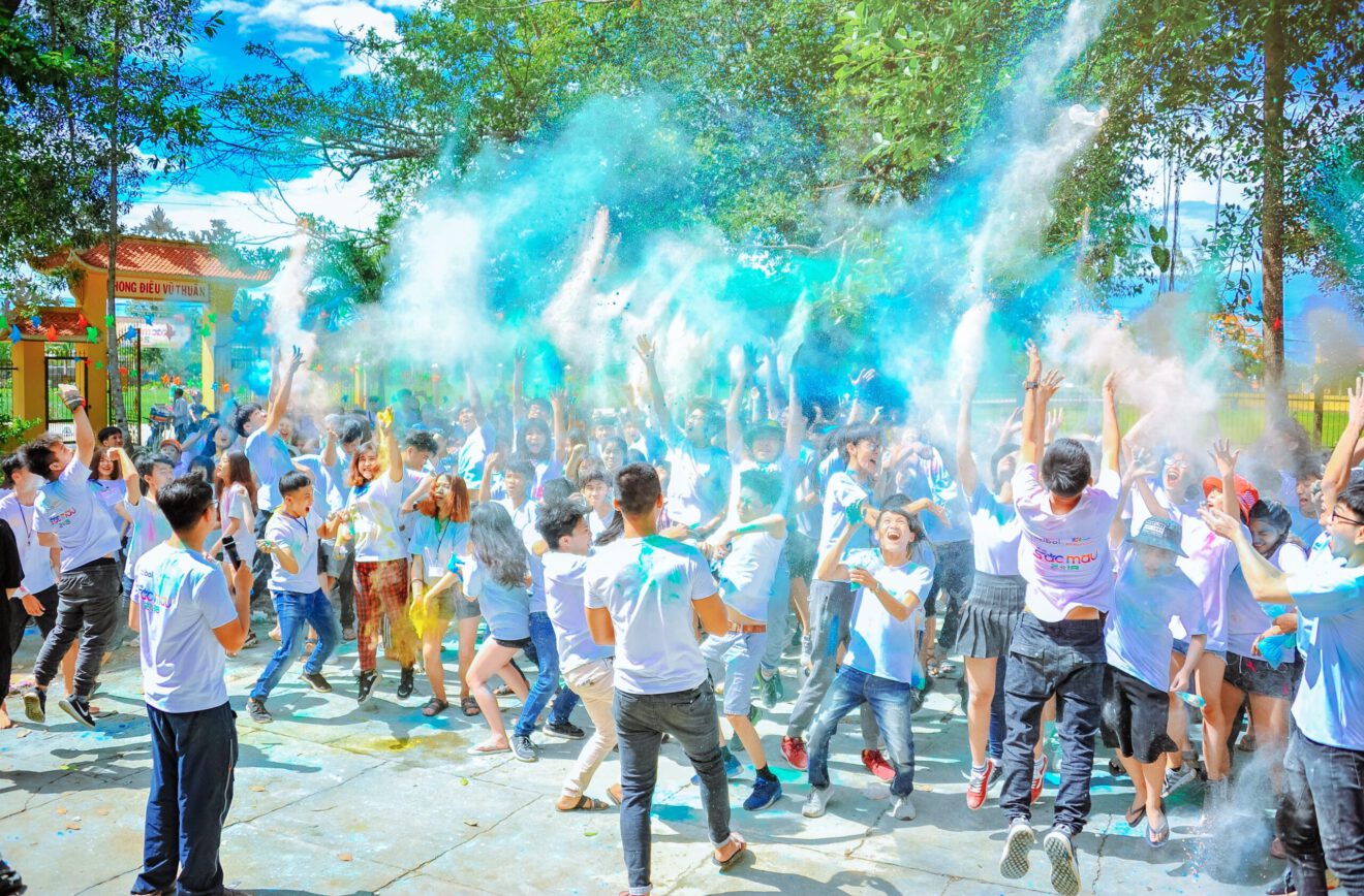 Photo of people outside throwing colored dust in the air at an event