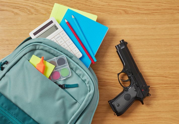photo illustration of Backpack, school supplies and gun on desk for threat assessment article