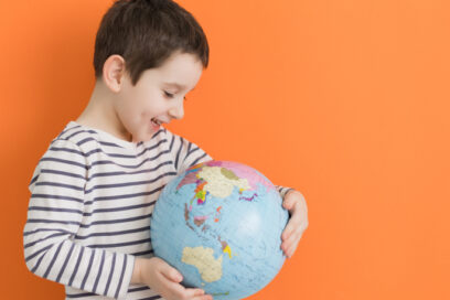 boy in striped shirt holding a globe for article on dual immersion
