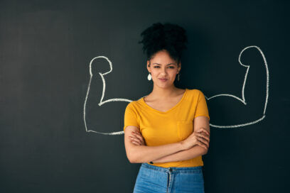 Shot of a woman posing with a chalk illustration of flexing muscles against a dark background for article on power at work