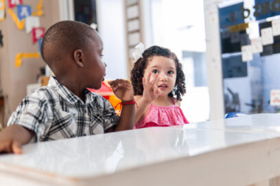 A black little boy and little hispanic girl learning maths in class.