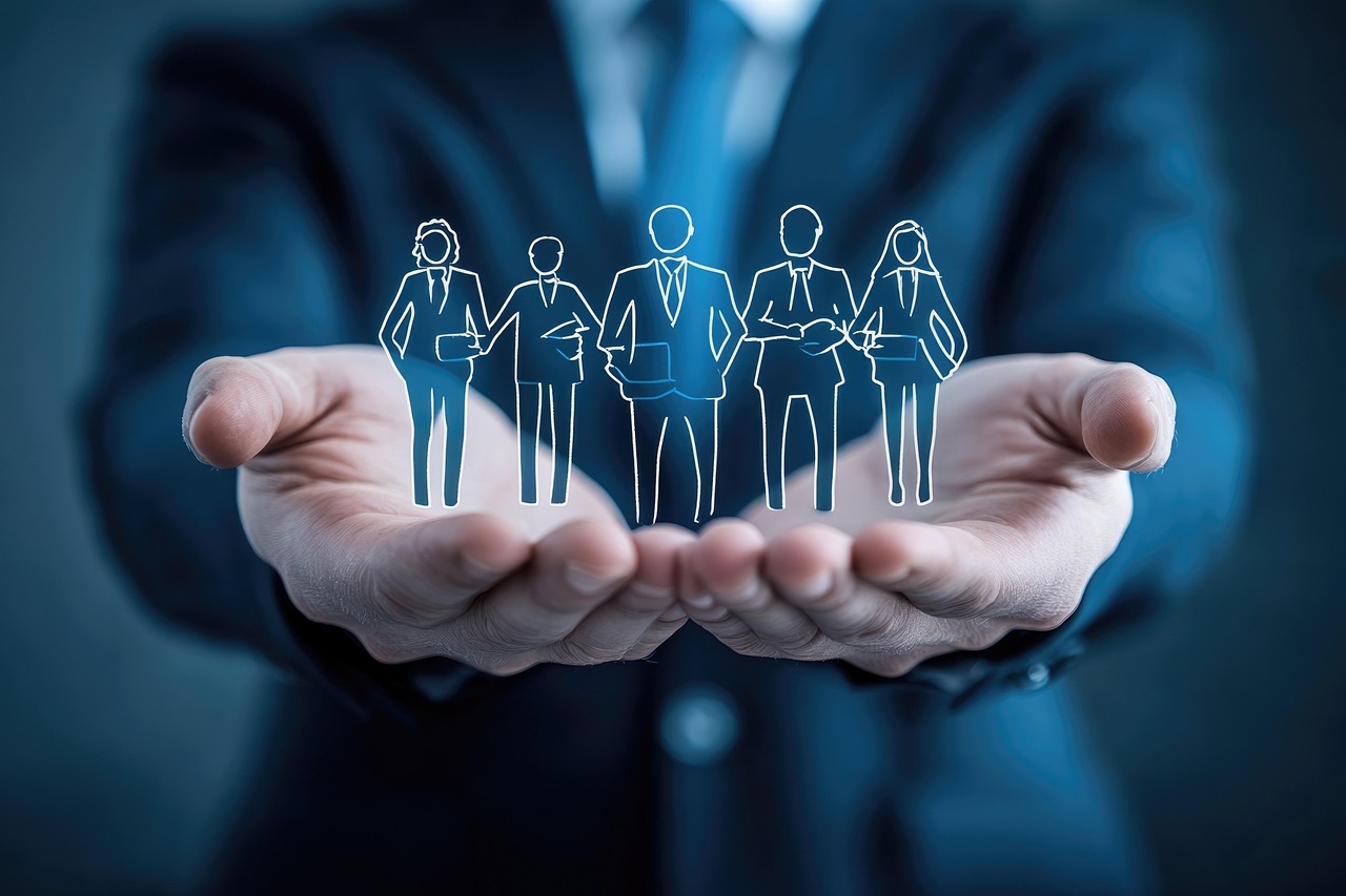 A businessman holding cutouts of people in his hands