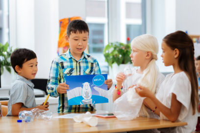 4 elementary school children of different nationalities working on school project together at a table.