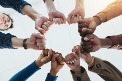 Business and people in a circle (only hands and wrists visible) with fists together