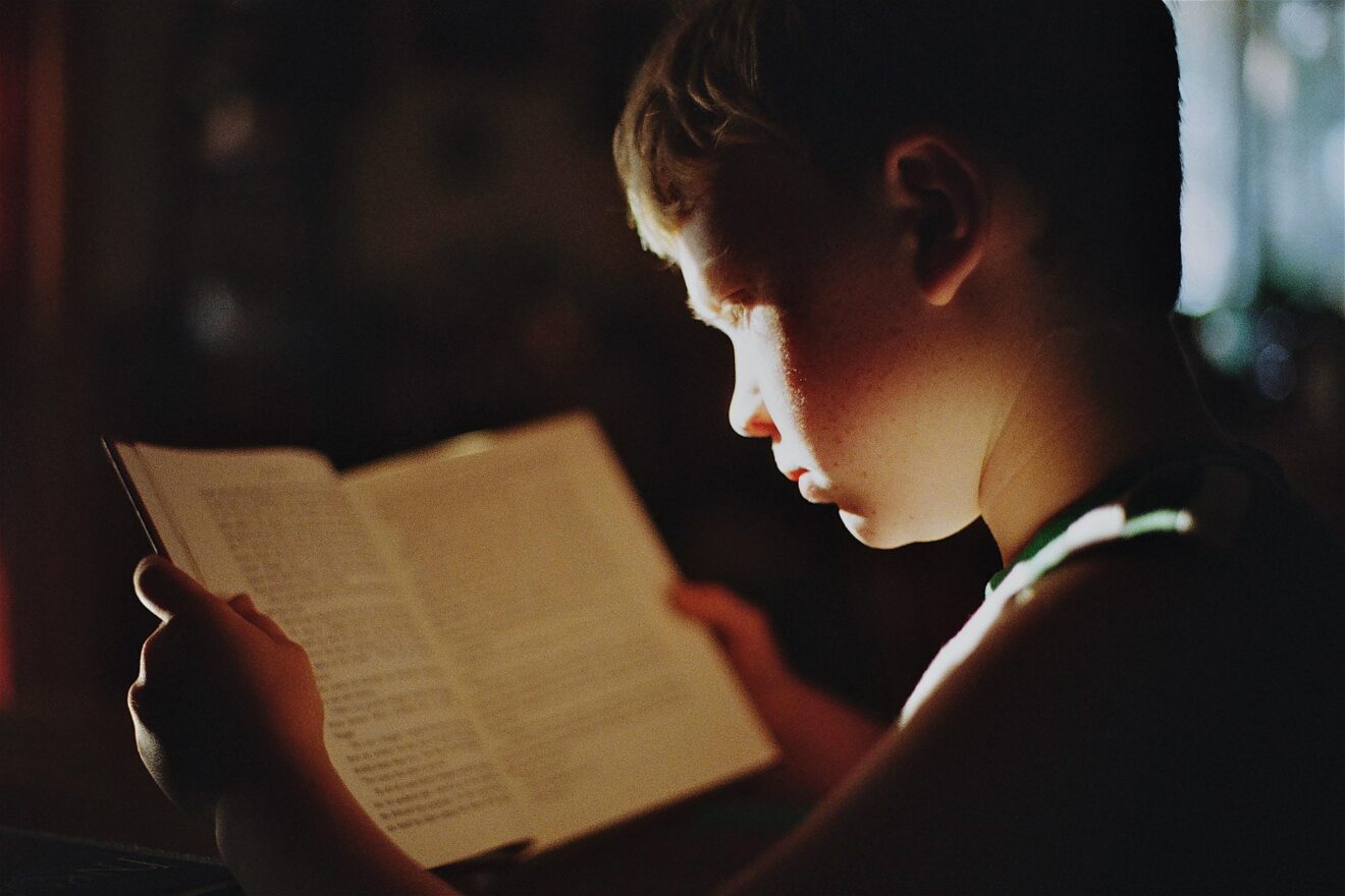 A boy reading in a shaft of sunlight