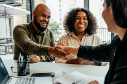 Financial professional shakes hands with a smiling client during a successful consultation meeting.
