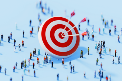 Large red and white bullseye target standing upright on a light blue surface. Three arrows are hit directly in the center of the target, while numerous tiny, miniature figures of people are scattered all around it.