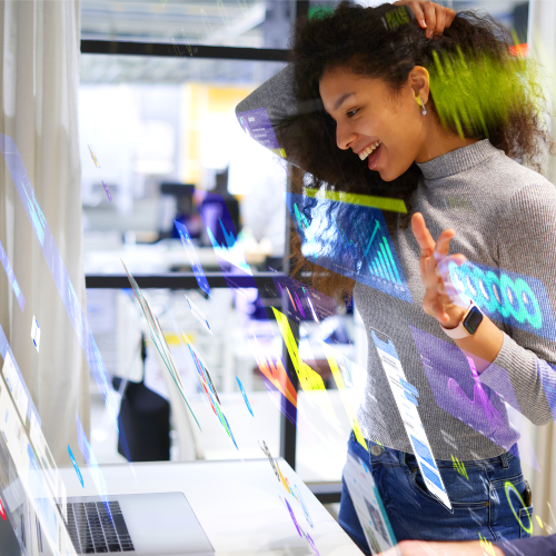 Person smiling while interacting with digital graphics on a transparent display in a modern office.