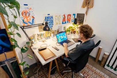 Young adult male illustrator working at the desk in a small workshop at home. Used for SmartBrief Marketing Original headline: Why human creativity still beats AI