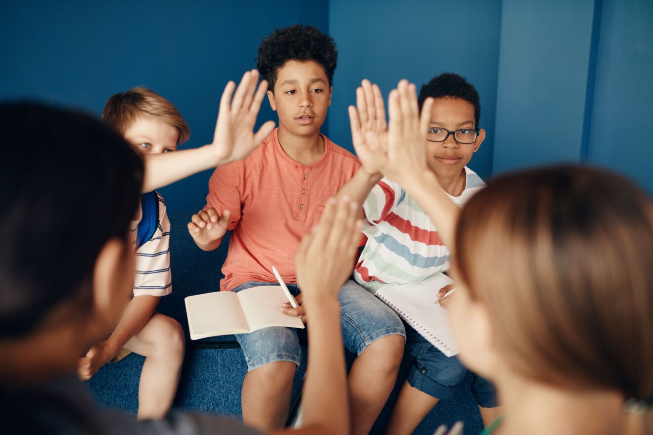 Students raising hands in class.