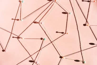 Abstract composition with strings connected by pins on a soft pastel background, forming a geometric web with sharp shadows in natural light. Concept of connection.