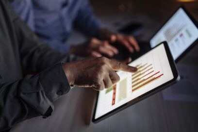 Close-up view of individuals reviewing data visualizations on digital tablets, signifying collaboration and analytical decision-making in a professional setting