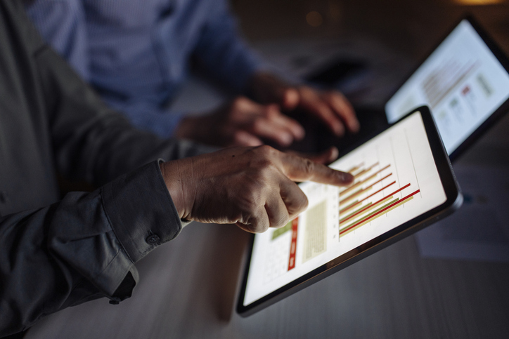 Close-up view of individuals reviewing data visualizations on digital tablets, signifying collaboration and analytical decision-making in a professional setting