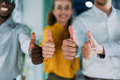 Shot of successful multi-ethnic business team showing thumbs up sign at work. Portrait of a group of business people showing thumbs up in the office. Focus is on the thumbs.