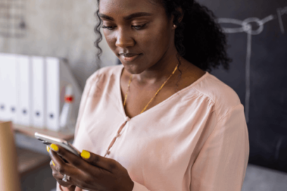 Young female teacher reading emails on her mobile device in her classroom, and considering EdTech purchasing
