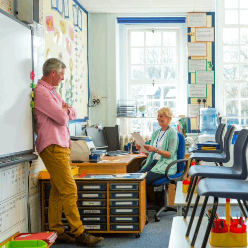 Two teachers discussing K-12 buying trends in a classroom