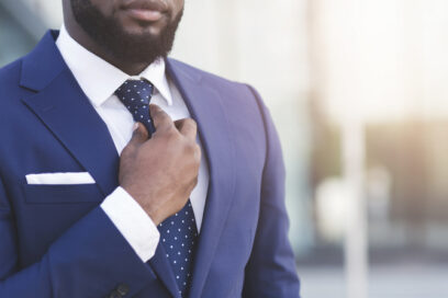 Unrecognizable Bearded Black Businessman Adjusting Tie Standing In Urban Area.