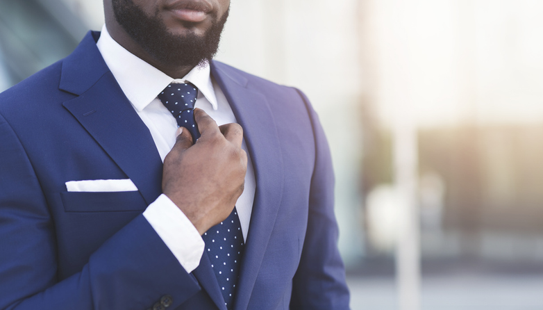 Unrecognizable Bearded Black Businessman Adjusting Tie Standing In Urban Area.